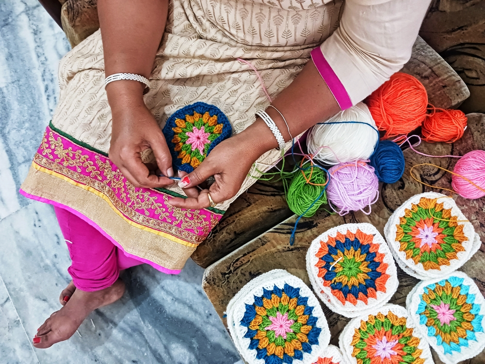 Woman crocheting squares for a blanket | Swoosh Finance