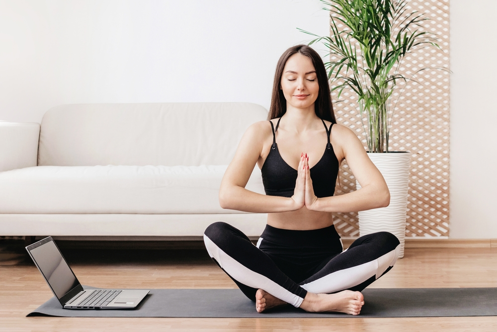 Woman doing yoga in her living room | Swoosh Finance