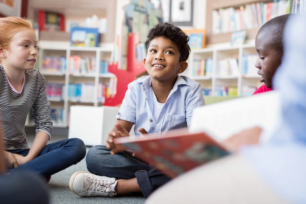 Kids listening to an adult read them a story at the local library | Swoosh Finance