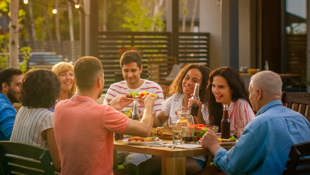 Friends having a potlucky dinner party in the backyard | Swoosh Finance