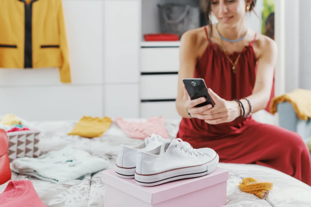 Woman in red dress takes pictures of a pair of white shoes she plans to sell